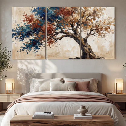 A broad tree with rust, blue and ochre foliage against warm cream 3 piece canvas wall art displayed in a bedroom