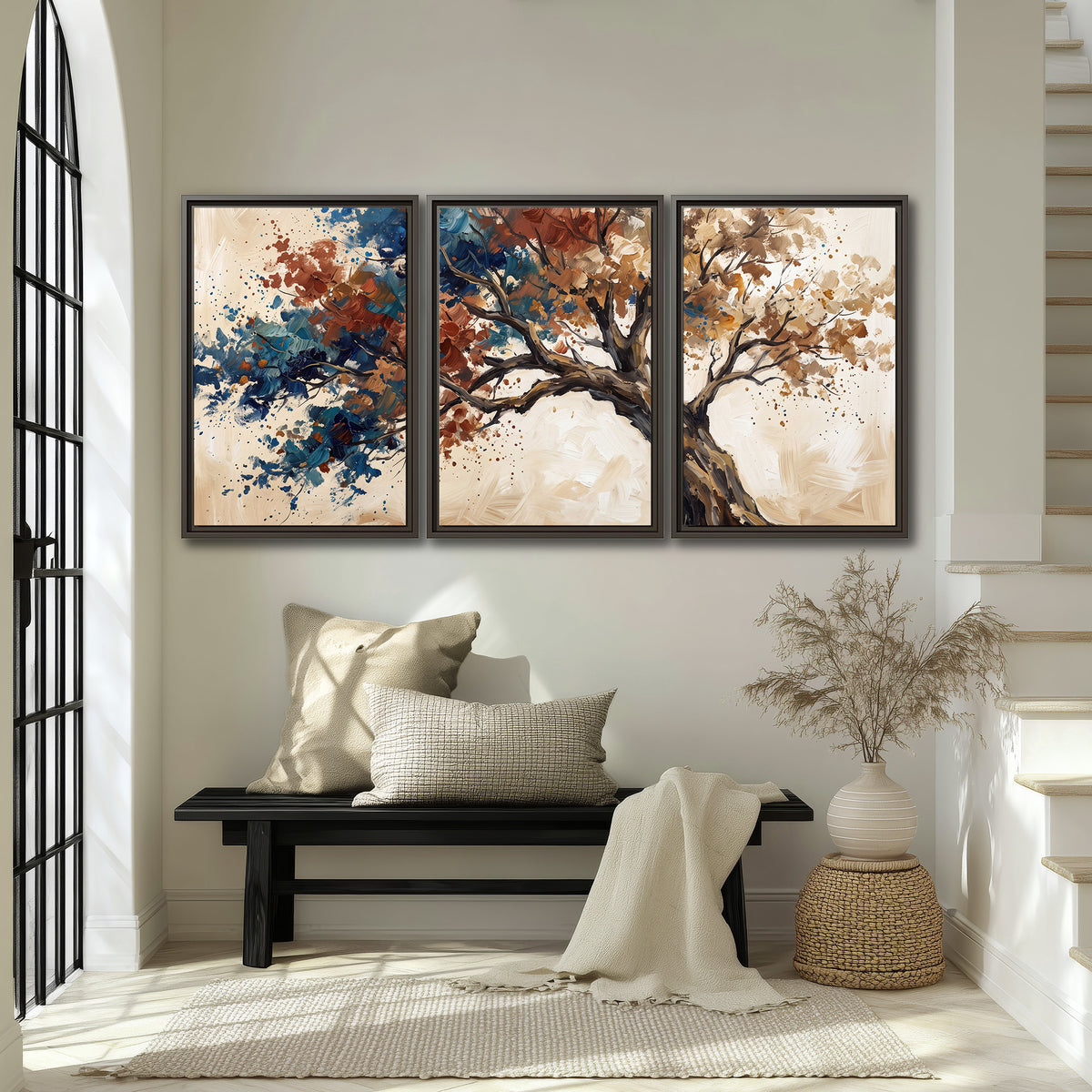 A broad tree with rust, blue and ochre foliage against warm cream 3 piece framed canvas wall art displayed in a entryway