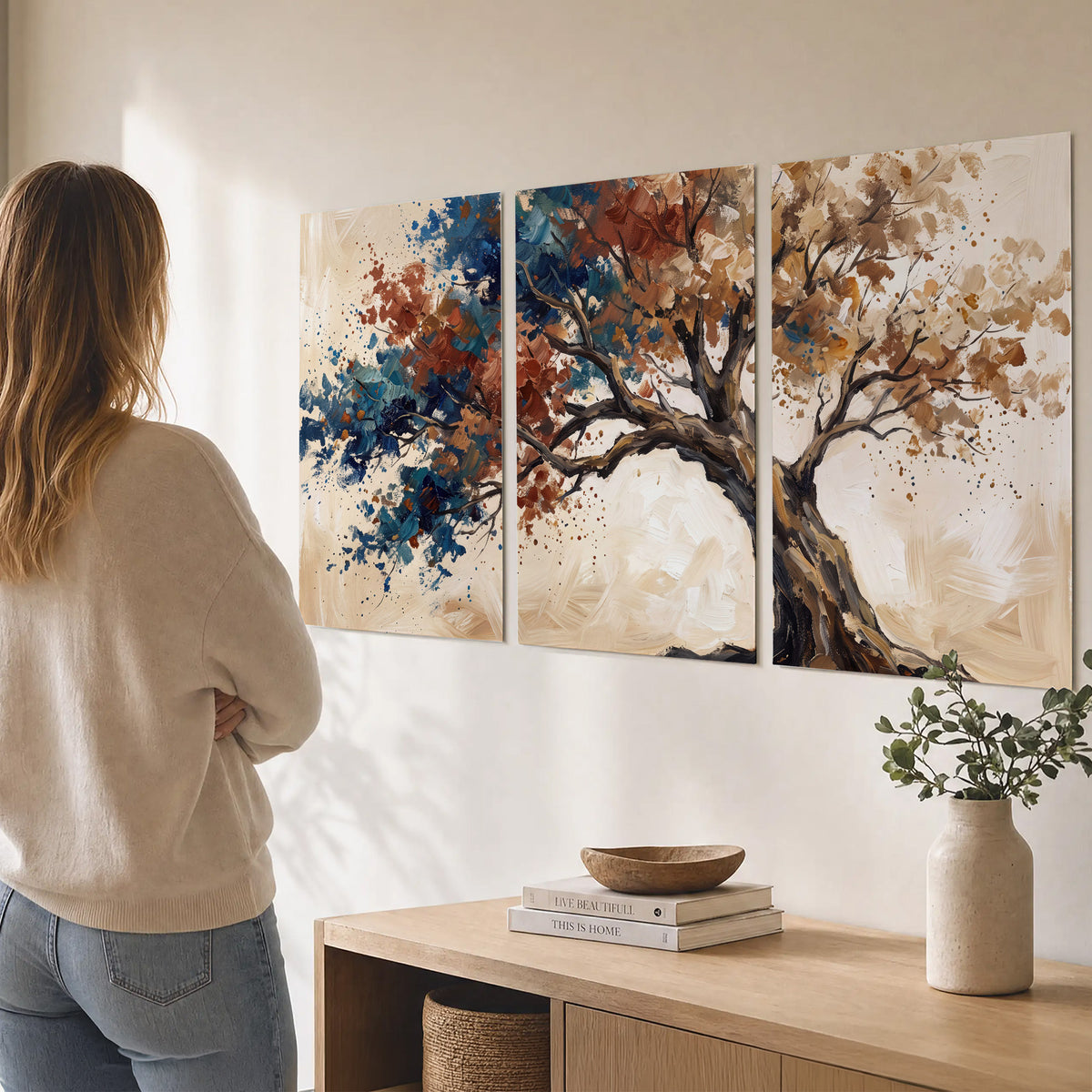 A broad tree with rust, blue and ochre foliage against warm cream set of 3 poster prints three panel arrangement on a wall