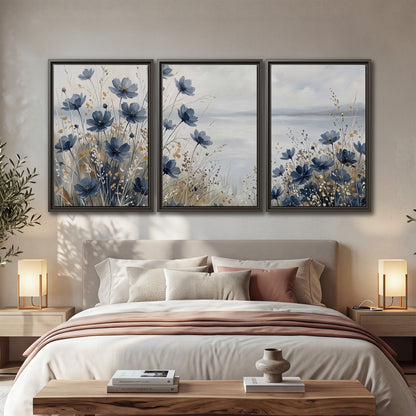 Soft blue flowers and ivory grasses beside a pale coastal horizon 3 piece framed canvas wall art displayed in a bedroom