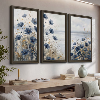 Soft blue flowers and ivory grasses beside a pale coastal horizon 3 piece framed canvas wall art displayed in a console
