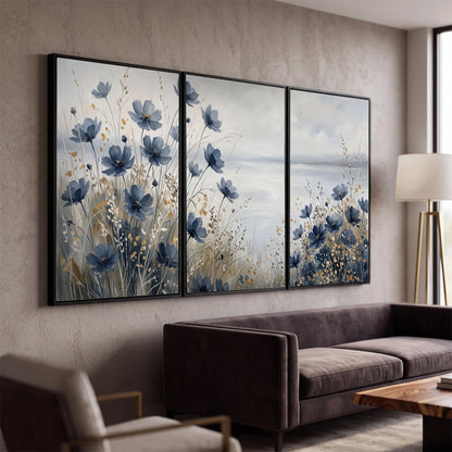 Soft blue flowers and ivory grasses beside a pale coastal horizon 3 piece framed canvas wall art displayed in a modern living room