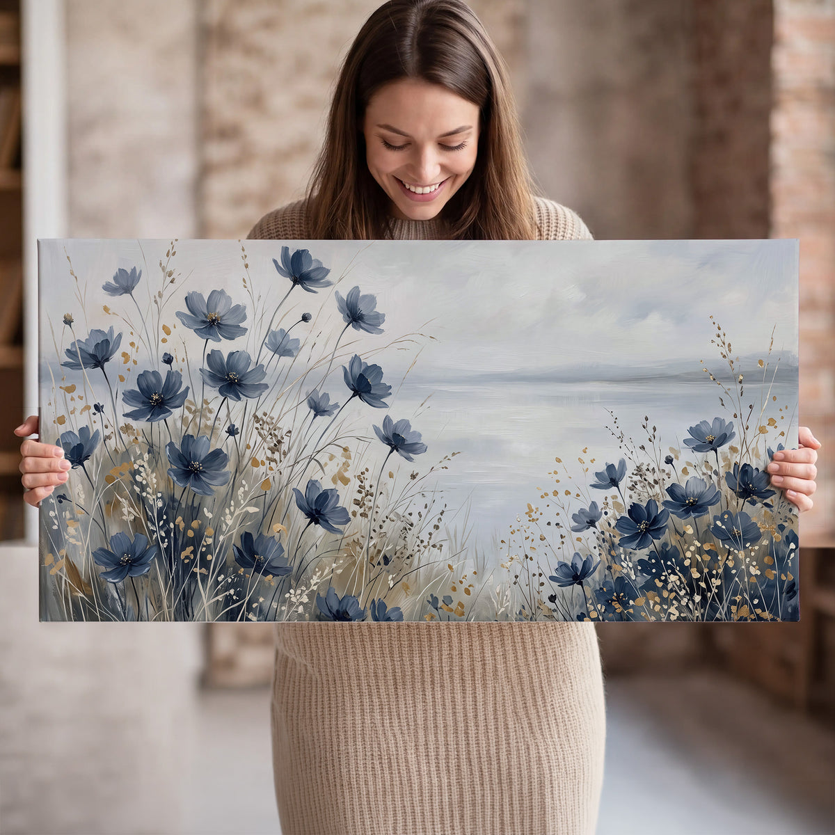 Soft blue flowers and ivory grasses beside a pale coastal horizon single canvas wall art held in hands