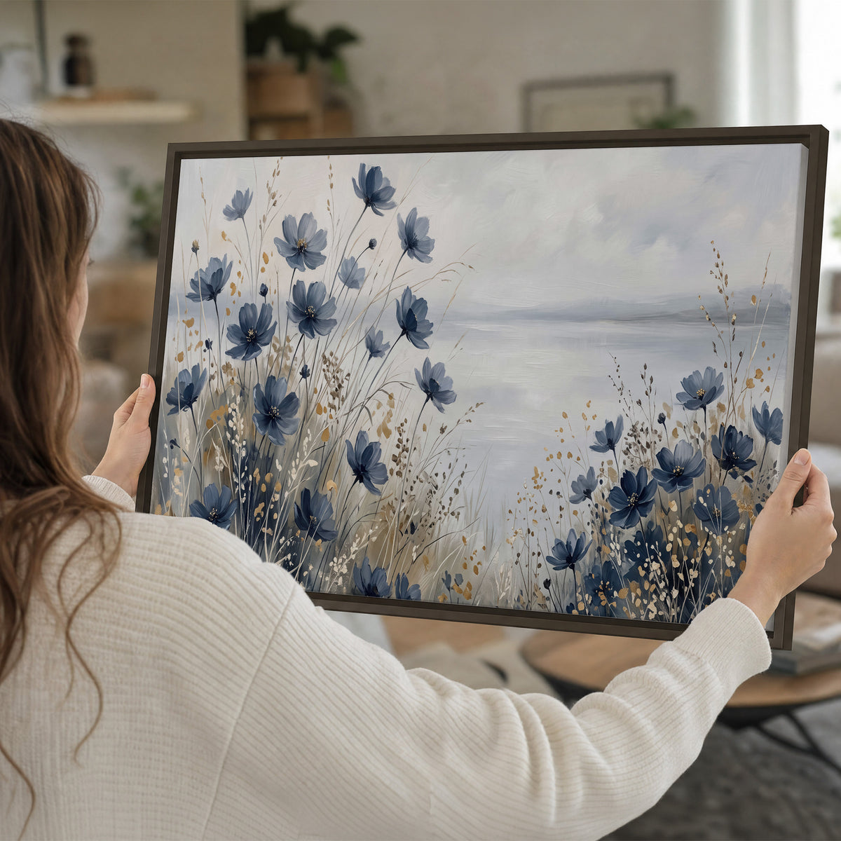 Soft blue flowers and ivory grasses beside a pale coastal horizon single framed canvas wall art held in hands