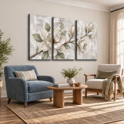 Large ivory magnolia blossoms and soft green leaves on pale gray 3 piece canvas wall art styled in an interior