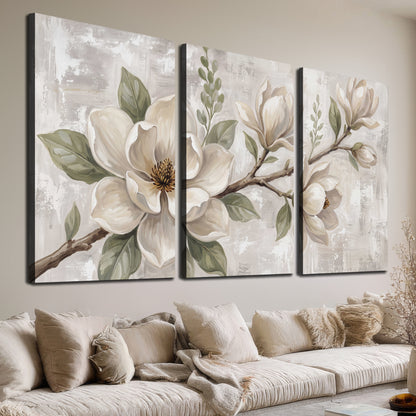Large ivory magnolia blossoms and soft green leaves on pale gray 3 piece canvas wall art room and product view