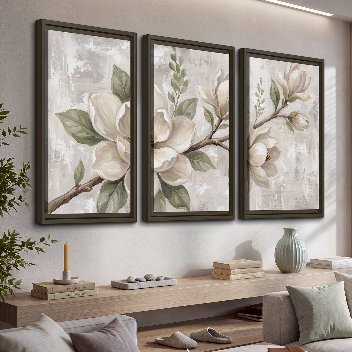 Large ivory magnolia blossoms and soft green leaves on pale gray 3 piece framed canvas wall art displayed in a console