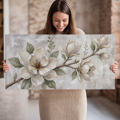 Large ivory magnolia blossoms and soft green leaves on pale gray single canvas wall art held in hands