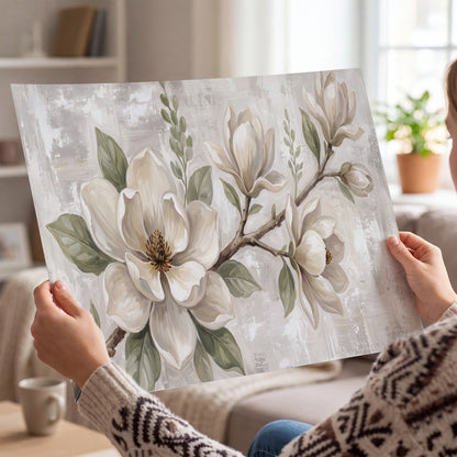 Large ivory magnolia blossoms and soft green leaves on pale gray single poster print held in hands