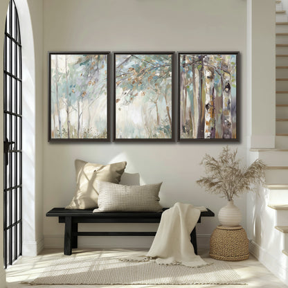 Slender woodland trunks and delicate branches in soft green and cream 3 piece framed canvas wall art displayed in a entryway