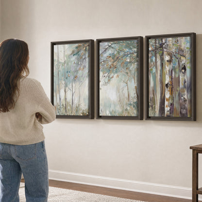 Slender woodland trunks and delicate branches in soft green and cream 3 piece framed canvas wall art three panel arrangement on a wall