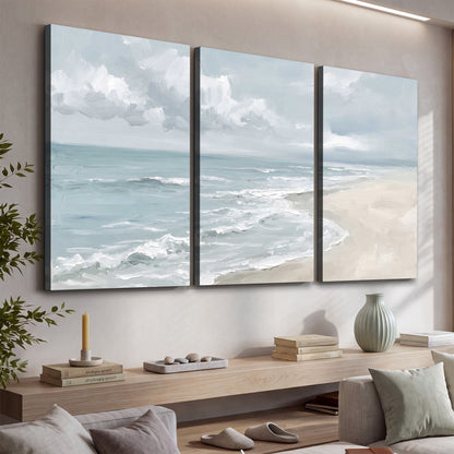 Gentle pale blue waves washing across a light sandy beach 3 piece canvas wall art displayed in a console