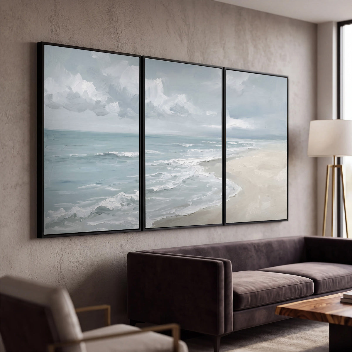 Gentle pale blue waves washing across a light sandy beach 3 piece framed canvas wall art displayed in a modern living room