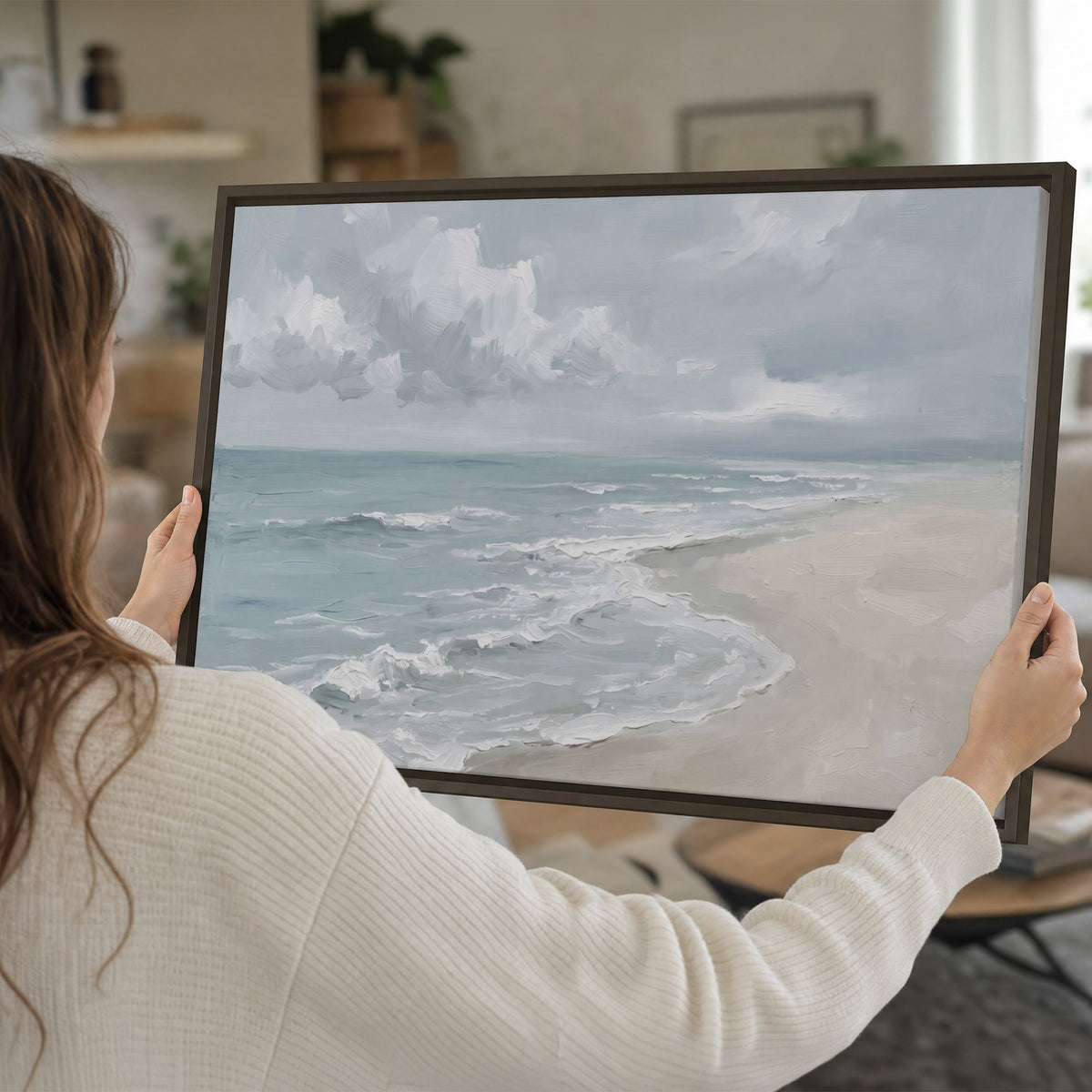 Gentle pale blue waves washing across a light sandy beach single framed canvas wall art held in hands