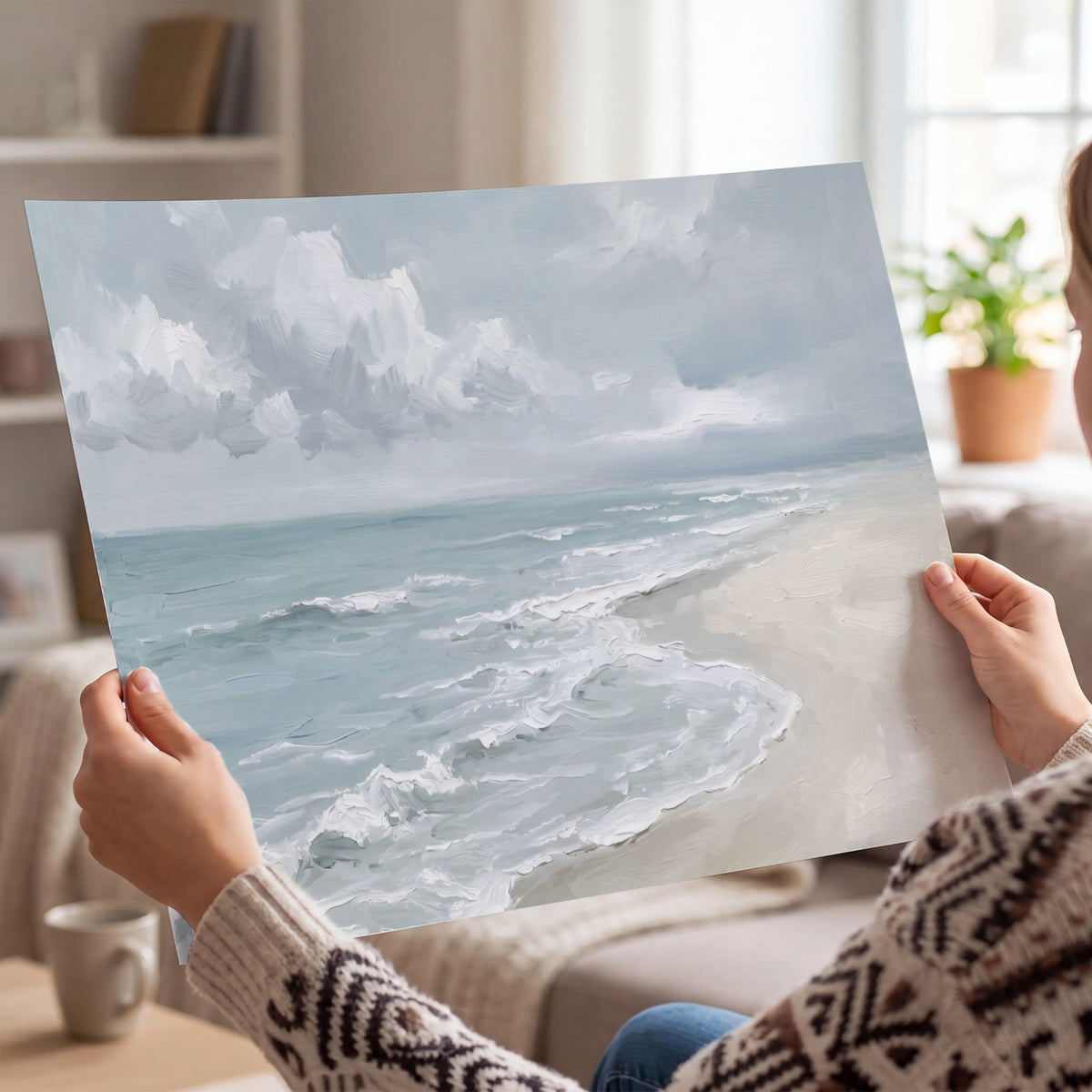 Gentle pale blue waves washing across a light sandy beach single poster print held in hands