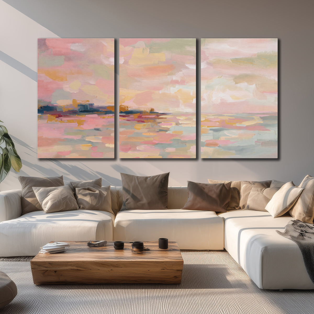 Pink, peach and yellow painted-style sky and water reflections 3 piece canvas wall art displayed in a living room
