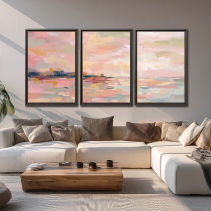 Pink, peach and yellow painted-style sky and water reflections 3 piece framed canvas wall art displayed in a living room