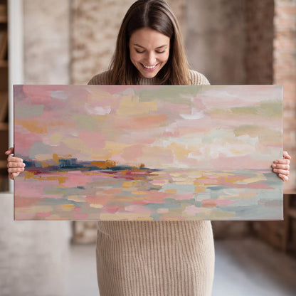 Pink, peach and yellow painted-style sky and water reflections single canvas wall art held in hands