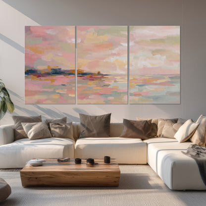 Pink, peach and yellow painted-style sky and water reflections set of 3 poster prints displayed in a living room