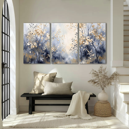 Delicate pale gold-colored branches against a deep blue misty background 3 piece canvas wall art displayed in a entryway