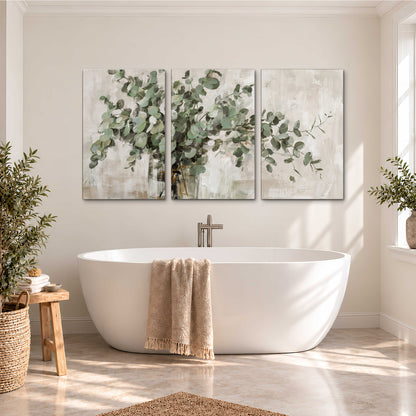 Soft sage eucalyptus leaves and pale stems on a warm cream background 3 piece canvas wall art styled in an interior