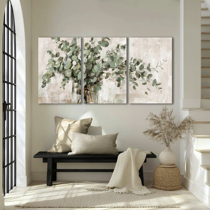 Soft sage eucalyptus leaves and pale stems on a warm cream background 3 piece canvas wall art displayed in a entryway