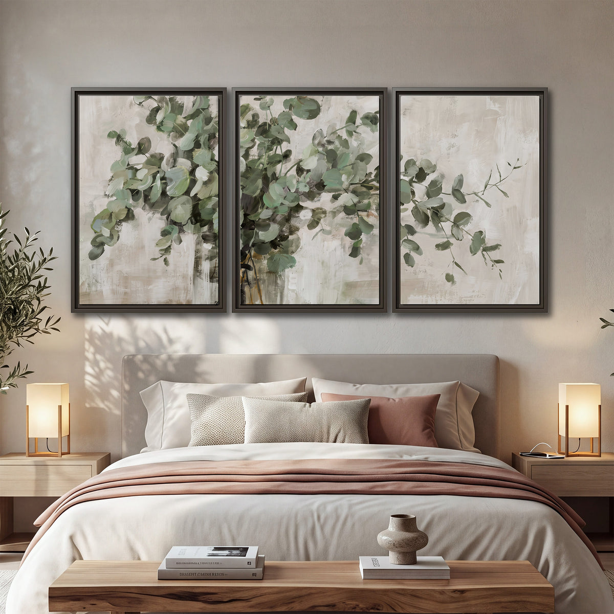Soft sage eucalyptus leaves and pale stems on a warm cream background 3 piece framed canvas wall art displayed in a bedroom