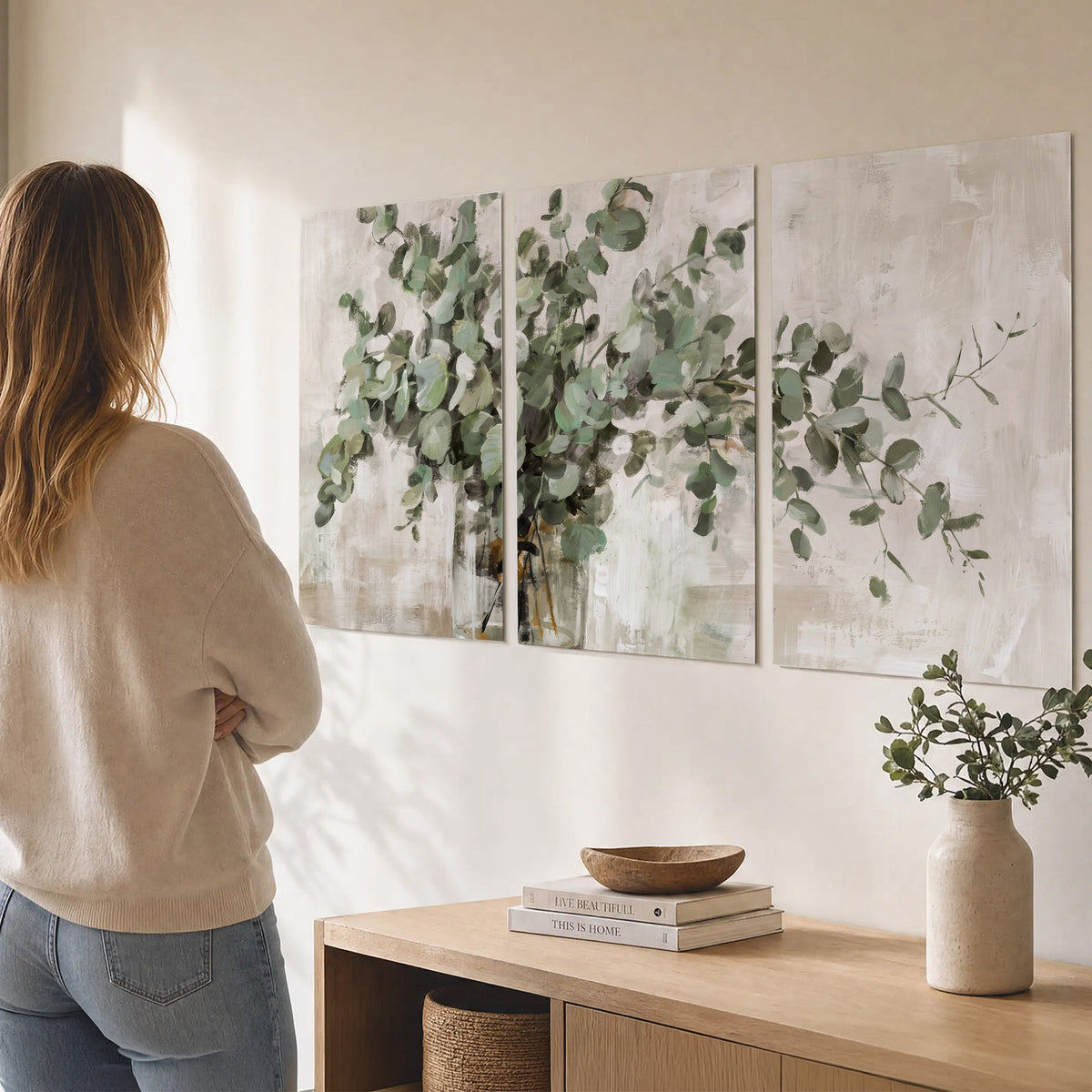 Soft sage eucalyptus leaves and pale stems on a warm cream background set of 3 poster prints three panel arrangement on a wall