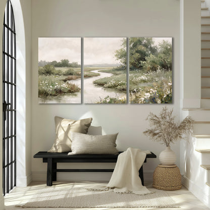 A narrow winding stream through quiet green meadows and trees 3 piece canvas wall art displayed in a entryway