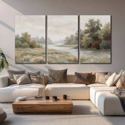 A broad pale river bordered by green trees and small meadow flowers 3 piece canvas wall art displayed in a living room
