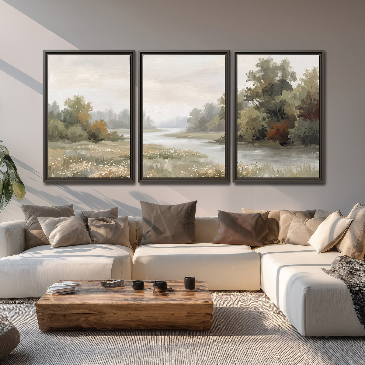 A broad pale river bordered by green trees and small meadow flowers 3 piece framed canvas wall art displayed in a living room