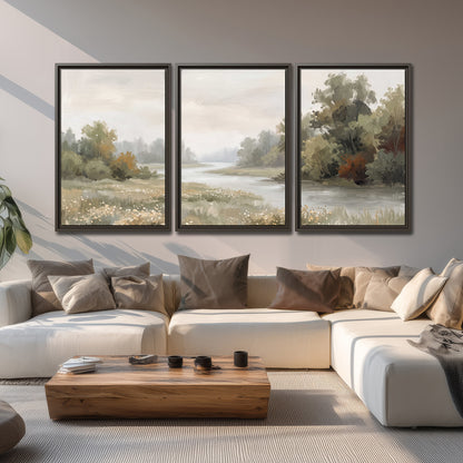 A broad pale river bordered by green trees and small meadow flowers 3 piece framed canvas wall art displayed in a living room