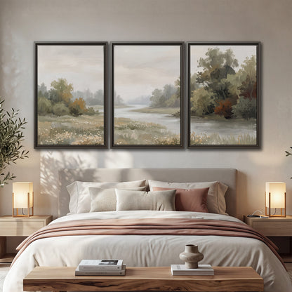 A broad pale river bordered by green trees and small meadow flowers 3 piece framed canvas wall art displayed in a bedroom