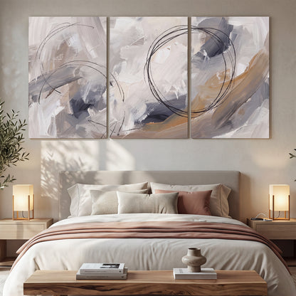 Expressive gray and cream abstract forms with fine gold-colored circular lines 3 piece canvas wall art displayed in a bedroom