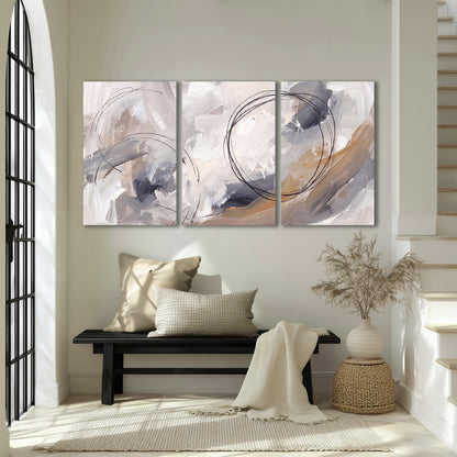 Expressive gray and cream abstract forms with fine gold-colored circular lines 3 piece canvas wall art displayed in a entryway