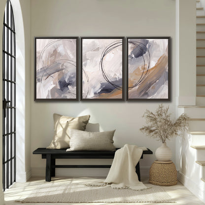 Expressive gray and cream abstract forms with fine gold-colored circular lines 3 piece framed canvas wall art displayed in a entryway