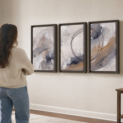 Expressive gray and cream abstract forms with fine gold-colored circular lines 3 piece framed canvas wall art three panel arrangement on a wall