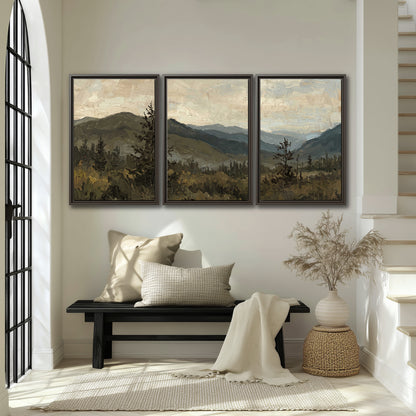 Layered mountain ridges and dark evergreen trees beneath a muted cloudy sky 3 piece framed canvas wall art displayed in a entryway