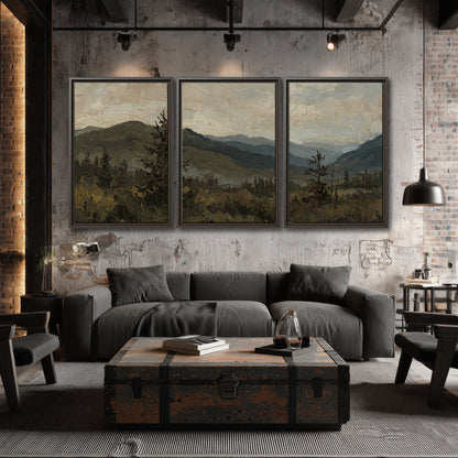 Layered mountain ridges and dark evergreen trees beneath a muted cloudy sky 3 piece framed canvas wall art displayed in a industrial room