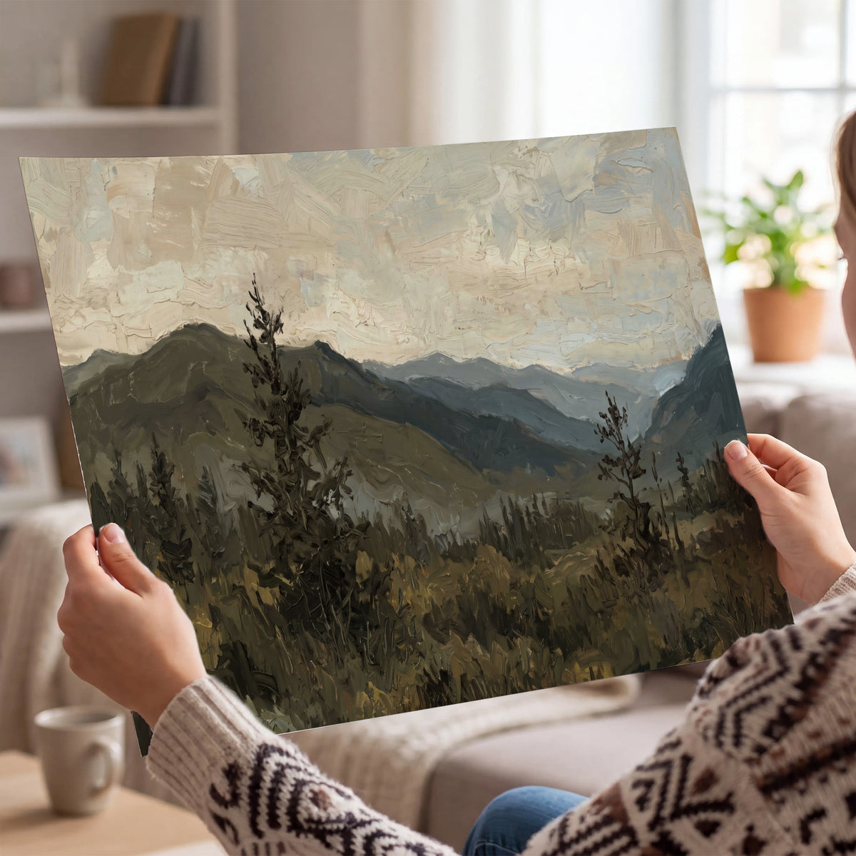 Layered mountain ridges and dark evergreen trees beneath a muted cloudy sky single poster print held in hands