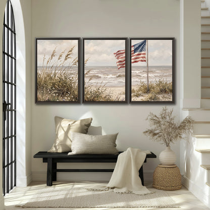 An American flag above coastal grasses beside a quiet sandy beach 3 piece framed canvas wall art displayed in a entryway