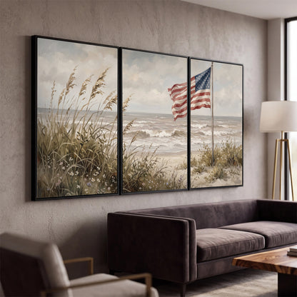 An American flag above coastal grasses beside a quiet sandy beach 3 piece framed canvas wall art displayed in a modern living room