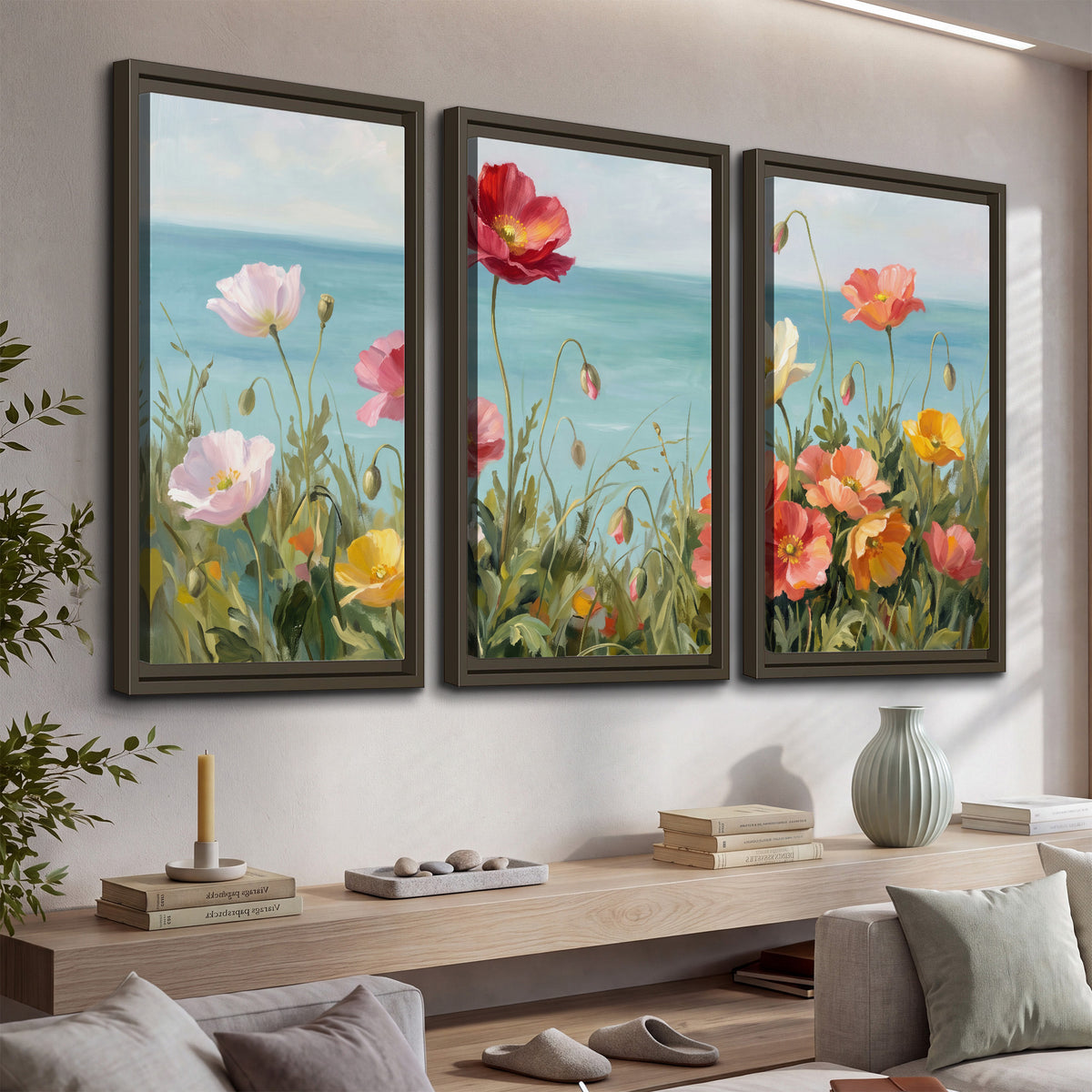 Colorful red, peach and yellow flowers beside a turquoise sea 3 piece framed canvas wall art displayed in a console