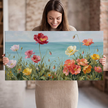 Colorful red, peach and yellow flowers beside a turquoise sea single canvas wall art held in hands