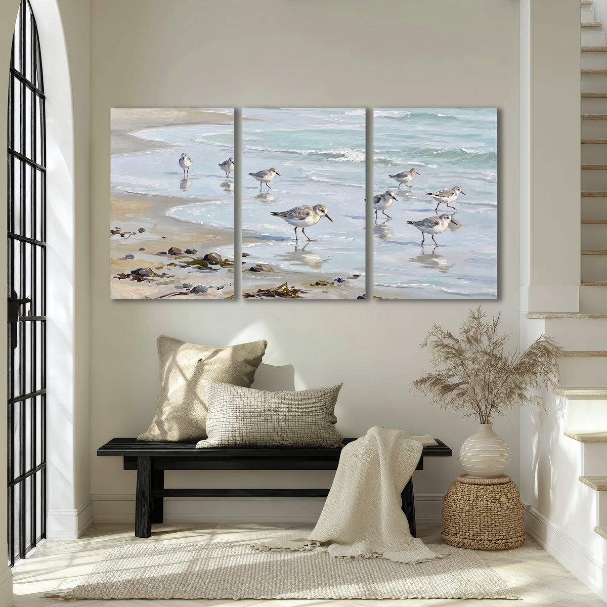 Small shorebirds standing along a pale blue shoreline 3 piece canvas wall art displayed in a entryway