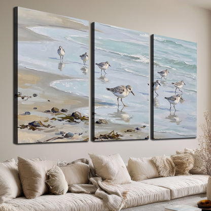 Small shorebirds standing along a pale blue shoreline 3 piece canvas wall art room and product view