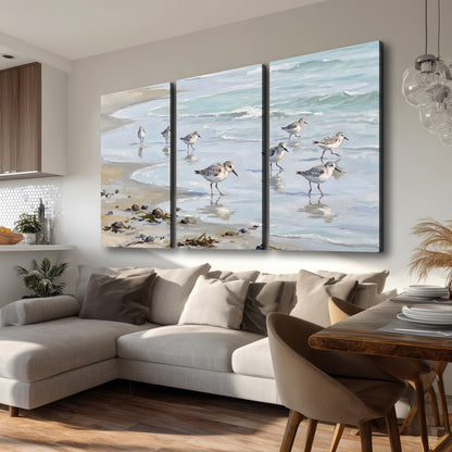 Small shorebirds standing along a pale blue shoreline 3 piece canvas wall art room and product view