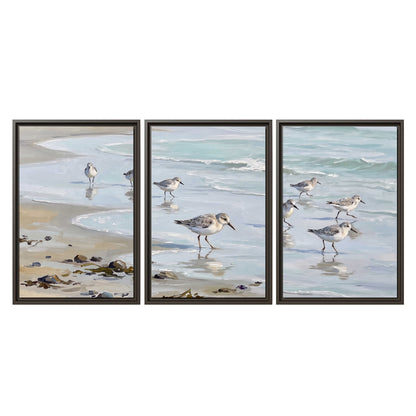 Small shorebirds standing along a pale blue shoreline 3 piece framed canvas wall art viewed straight on