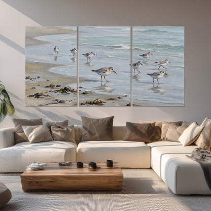 Small shorebirds standing along a pale blue shoreline set of 3 poster prints displayed in a living room