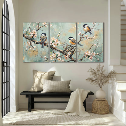 Small colorful songbirds perched among pale blossoms on soft aqua 3 piece canvas wall art displayed in a entryway